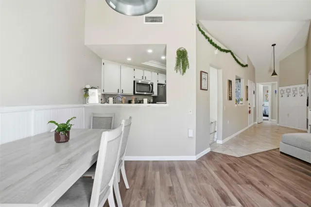a kitchen with stainless steel appliances a dining table chairs and wooden floor