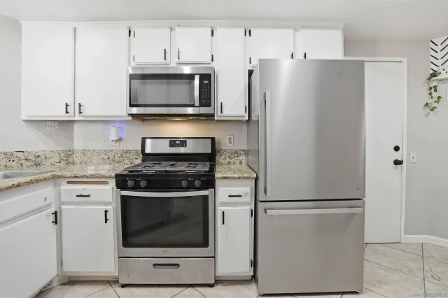 a kitchen with stainless steel appliances white cabinets white stove a microwave and a refrigerator