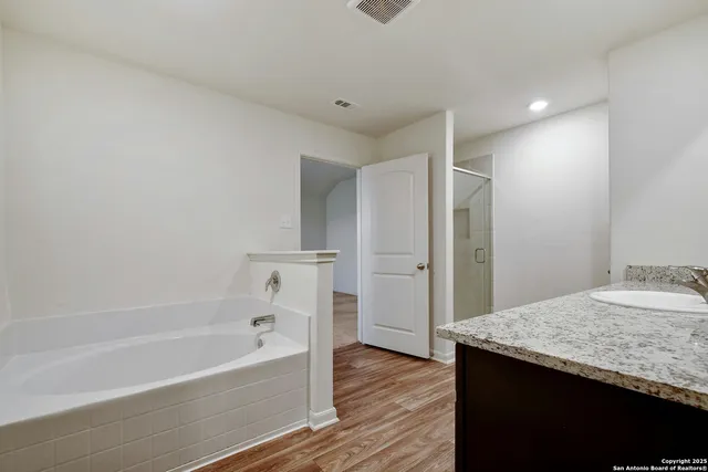 a bathroom with a granite countertop sink and a bathtub