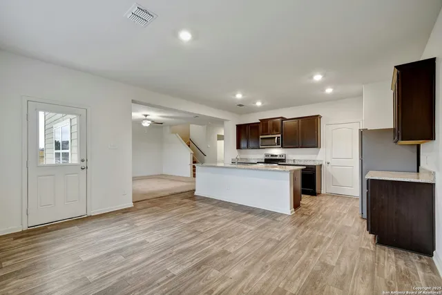 a large kitchen with stainless steel appliances kitchen island granite countertop a large counter top and wooden floors