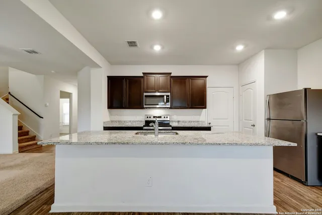 a kitchen with stainless steel appliances granite countertop a refrigerator and a sink