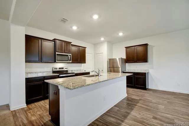 a large kitchen with stainless steel appliances granite countertop a stove a sink and a microwave