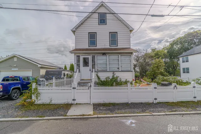 a view of a house with a small yard and large tree