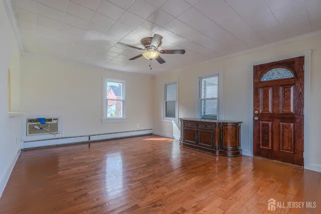 a view of an empty room with window and wooden floor