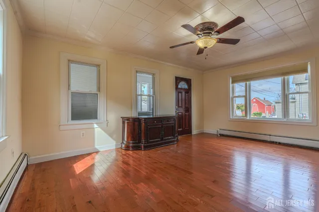 a view of an empty room with window and wooden floor