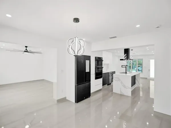 a view of kitchen with stainless steel appliances refrigerator oven and white cabinets with wooden floor
