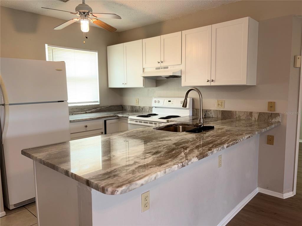 26485 Rampart Boulevard, Unit D1 Punta Gorda, FL 33983 - Photo 7 of 29 a kitchen with kitchen island granite countertop a sink a center island and cabinets