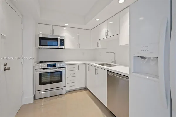 a kitchen with stainless steel appliances granite countertop white cabinets a microwave a sink and a refrigerator