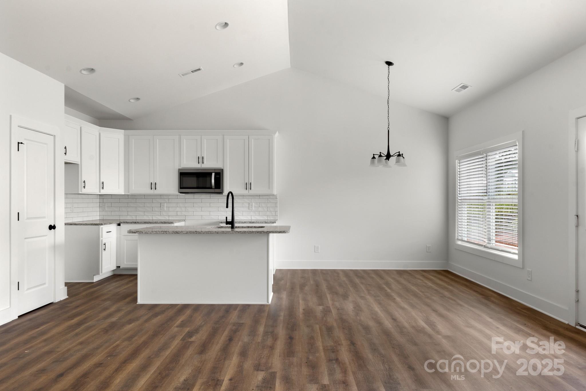 2508 Rock Dam Road Harmony, NC 28634 - Photo 6 of 32 a kitchen with stainless steel appliances granite countertop a sink a stove a refrigerator and white cabinets with wooden floor