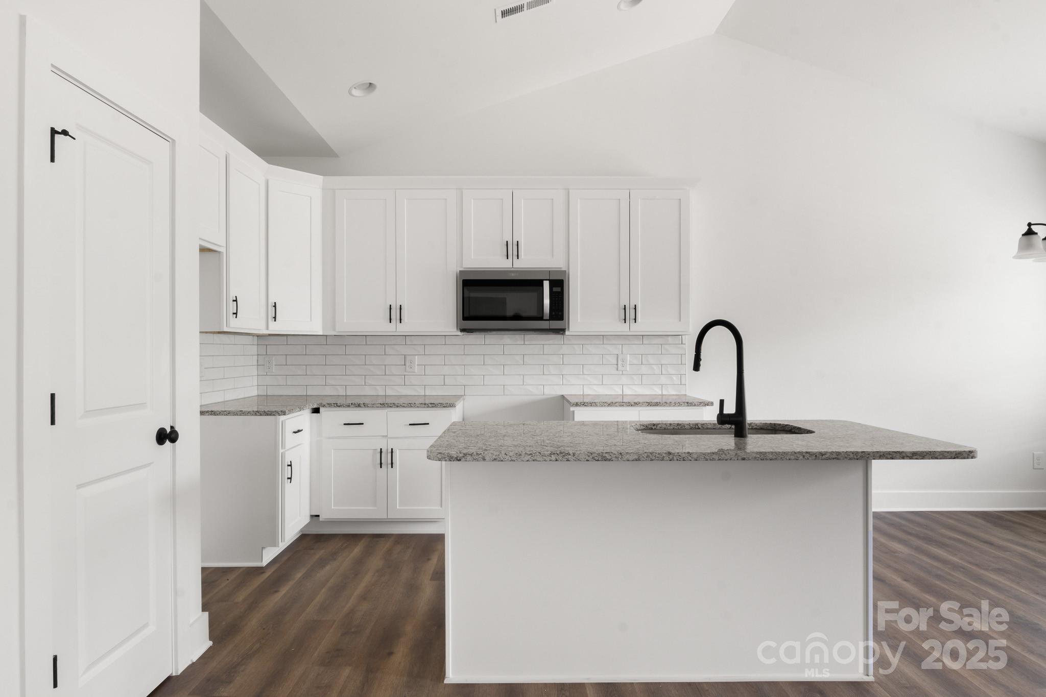 2508 Rock Dam Road Harmony, NC 28634 - Photo 10 of 32 a kitchen with stainless steel appliances granite countertop a sink a stove a refrigerator and white cabinets with wooden floor