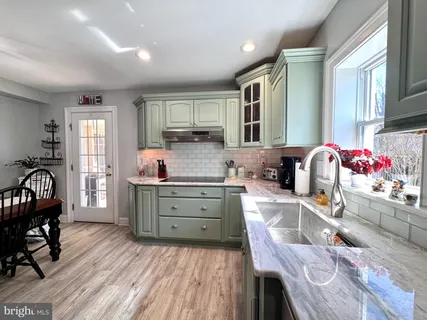a kitchen that has a lot of cabinets a sink and wooden floor