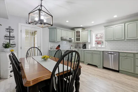 a kitchen with stainless steel appliances granite countertop a dining table chairs sink refrigerator and microwave
