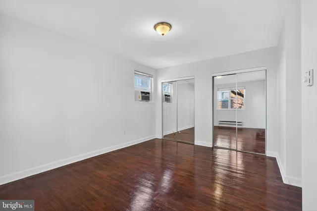 an empty room with wooden floor and mirror