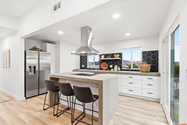 a kitchen with stainless steel appliances a table a refrigerator and cabinets