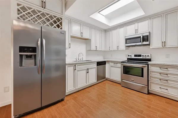 a kitchen with cabinets stainless steel appliances and wooden floor
