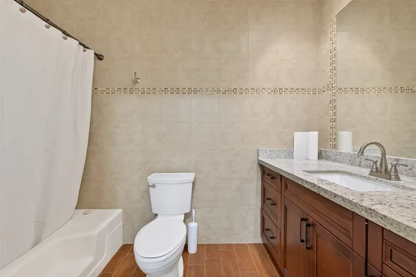 a bathroom with a granite countertop sink a toilet and a shower