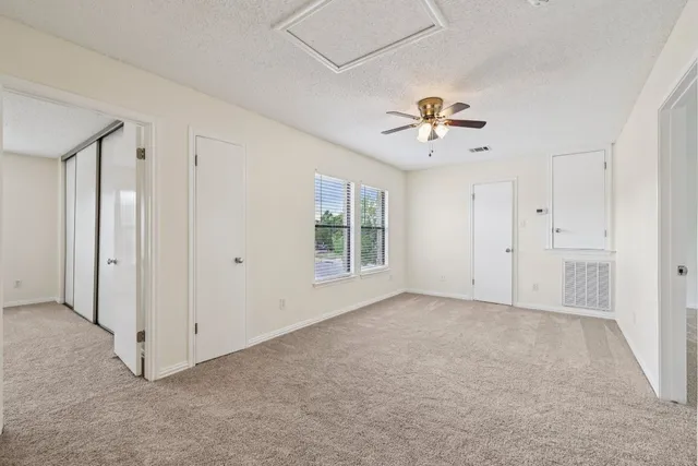 a view of an empty room with a ceiling fan and window