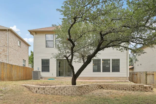 a backyard of a house with large trees and wooden fence