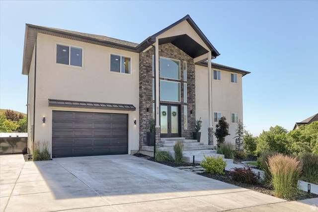 828 South Deer Road Tooele, UT 84074 - Photo 2 of 51 Contemporary residence featuring a prominent stone facade entrance with a two-story window array