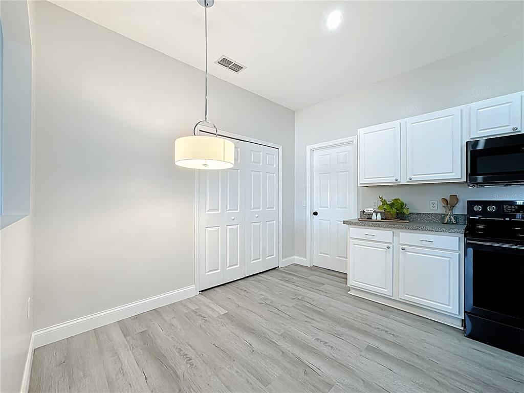 312 Towhee Road Winter Haven, FL 33881 - Photo 13 of 45 a kitchen with granite countertop a stove a sink and white cabinets with wooden floor