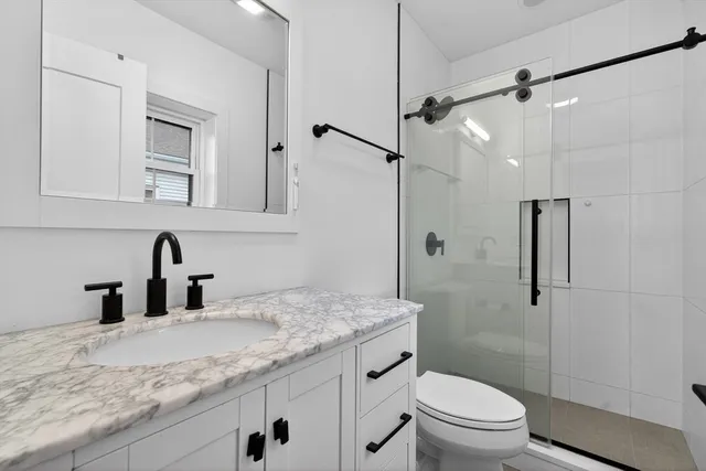 a bathroom with a granite countertop sink a toilet and shower