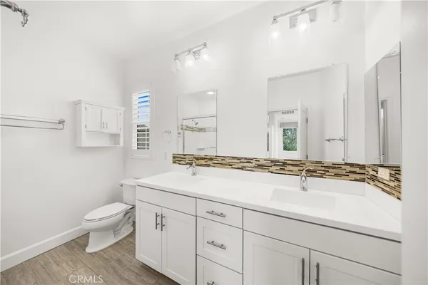 a spacious bathroom with a granite countertop sink a toilet a and mirror