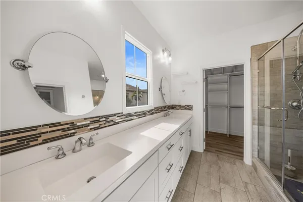 a spacious bathroom with a double vanity sink a mirror and a shower