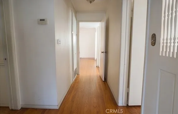 a view of a hallway with wooden floor and a bathroom