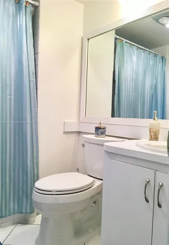 a bathroom with a sink a toilet a mirror and shower curtain