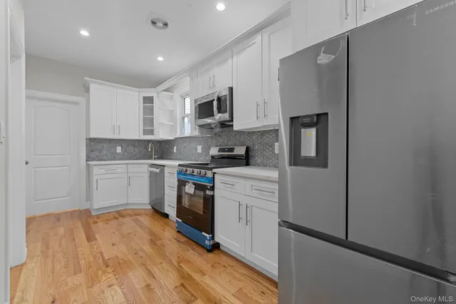 a kitchen with stainless steel appliances a sink cabinets and a wooden floor