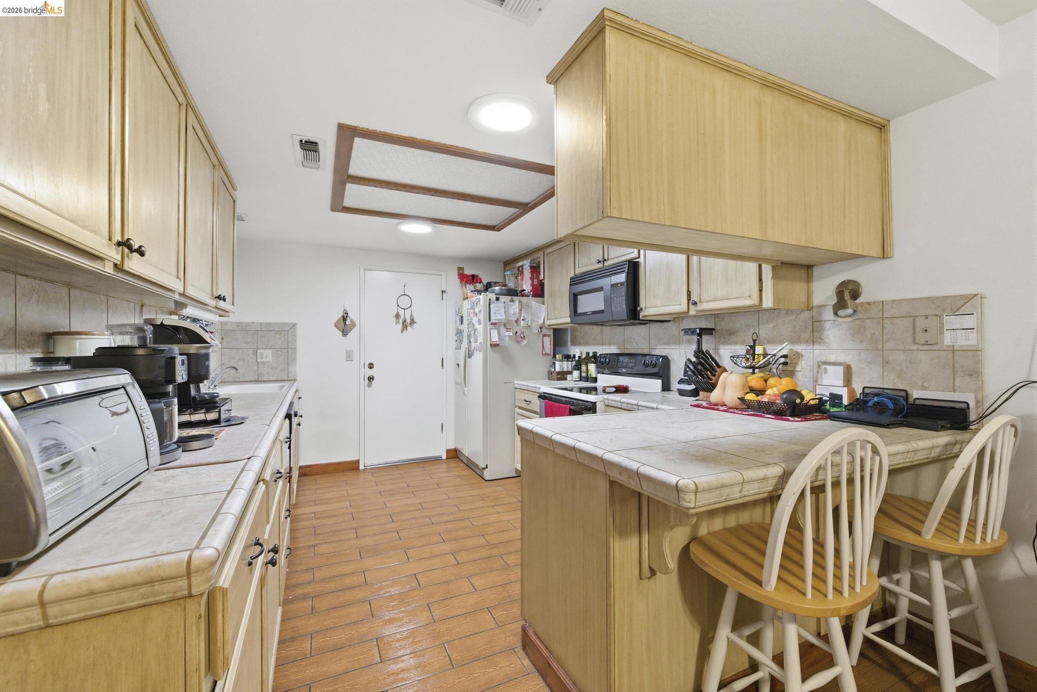 23685 Marble Quarry Road, Unit 8 Columbia, CA 95310 - Photo 5 of 25 a kitchen with stainless steel appliances a stove a refrigerator a sink a dining table and chairs with wooden floor