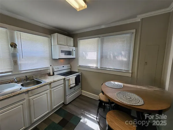 a kitchen with a sink a stove a window cabinets and a dining table