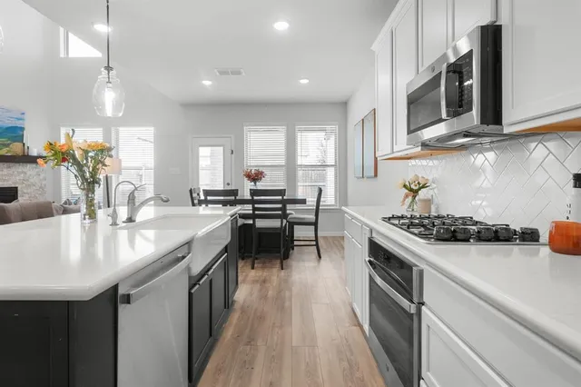 a kitchen with stainless steel appliances a sink stove and cabinets