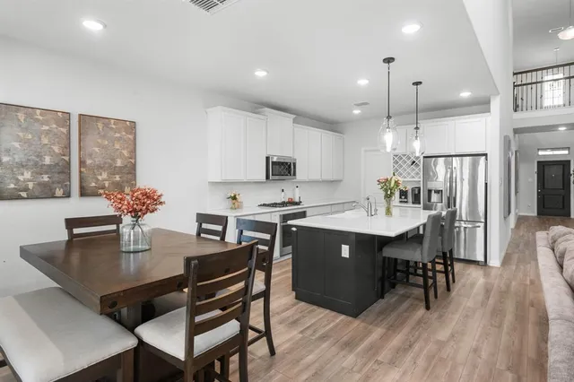 a kitchen with a dining table chairs and refrigerator