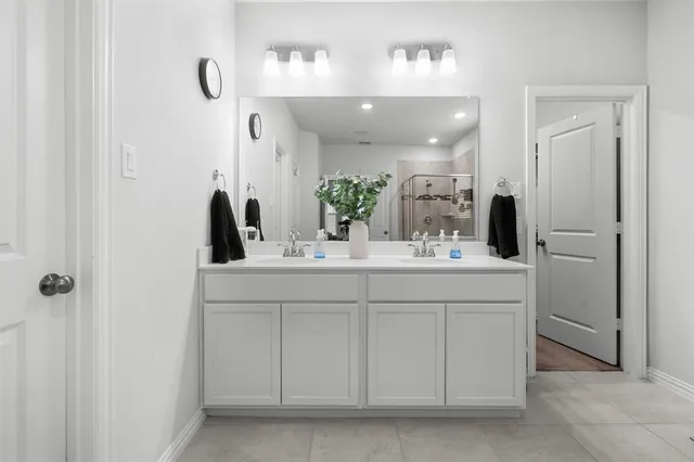 a bathroom with a double vanity sink a mirror and shower