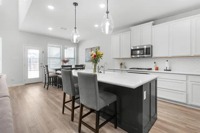 a kitchen with kitchen island granite countertop a sink a center island and appliances