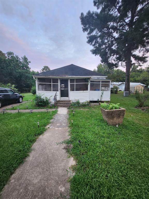 View of front facade with a sunroom and a yard