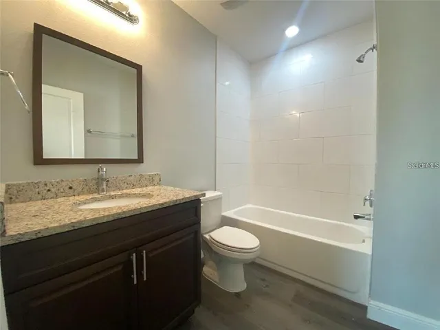 a bathroom with a granite countertop sink toilet mirror and bathtub