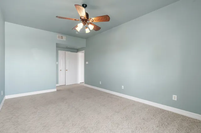 a view of an empty room with a chandelier fan
