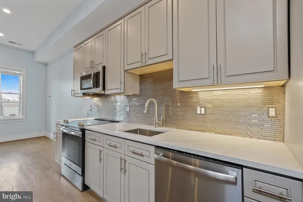 a kitchen with granite countertop white cabinets and stainless steel appliances