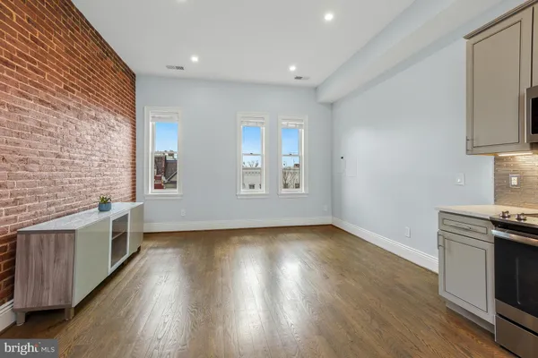 a view of an empty room with a window and wooden floor