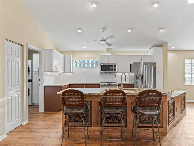 a kitchen with stainless steel appliances granite countertop a stove top oven a sink dishwasher a refrigerator and a oven with wooden floors