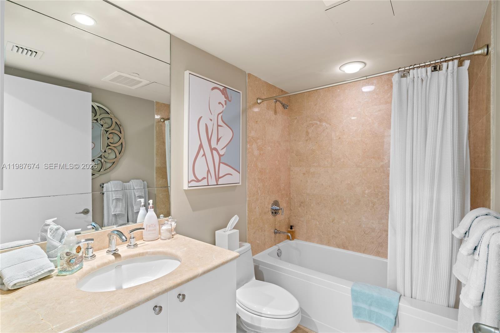 901 Brickell Key Boulevard, Unit 2804 Miami, FL 33131 - Photo 31 of 91 a bathroom with a sink a toilet a mirror a bathtub and shower