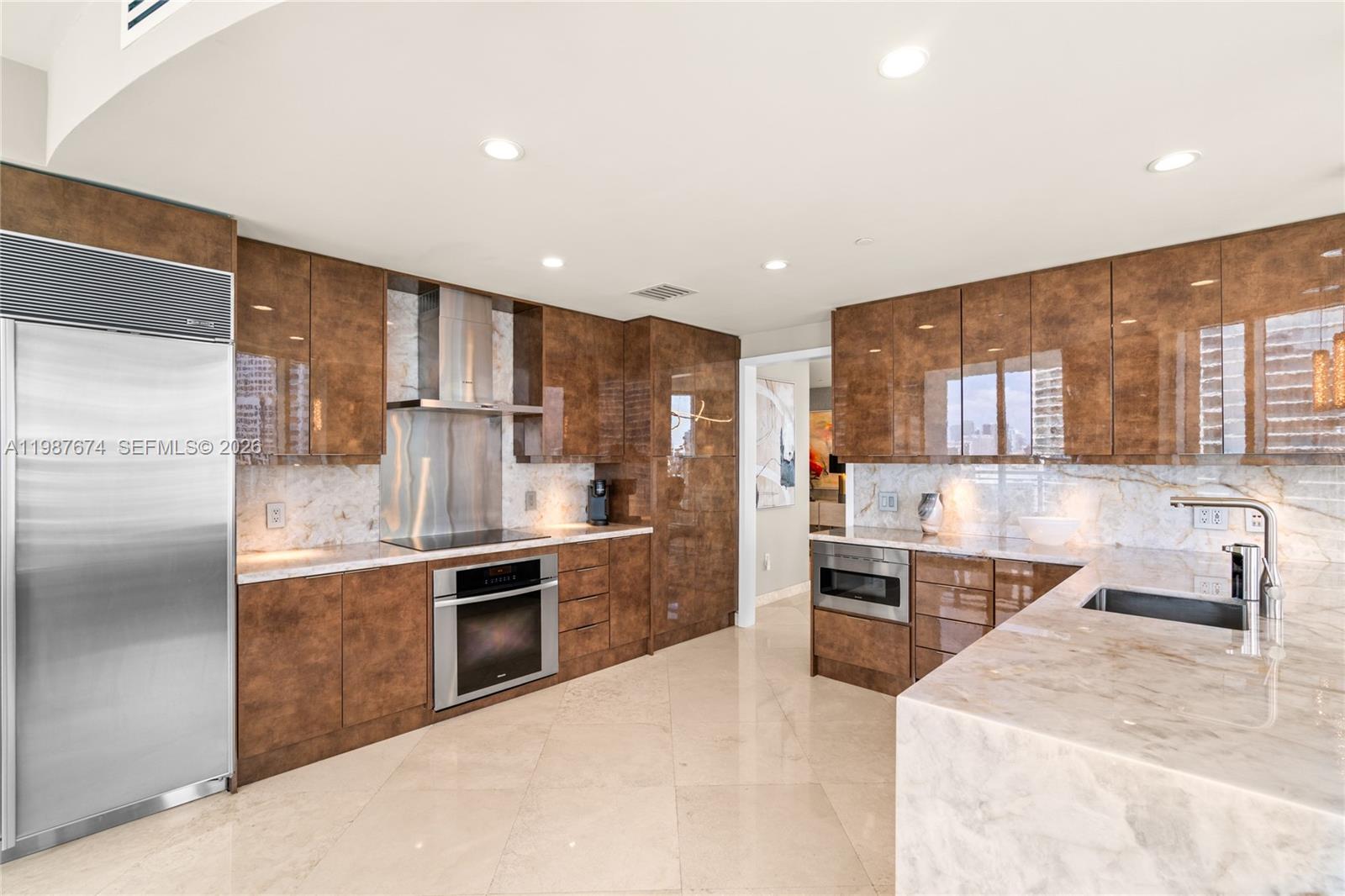 901 Brickell Key Boulevard, Unit 2804 Miami, FL 33131 - Photo 86 of 91 a kitchen with stainless steel appliances kitchen island granite countertop a refrigerator and a stove top oven