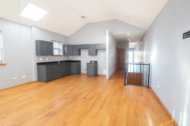 a view of a kitchen with kitchen island wooden floor center island and stainless steel appliances