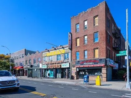 a view of street with large building and couple of cars parked in front of it