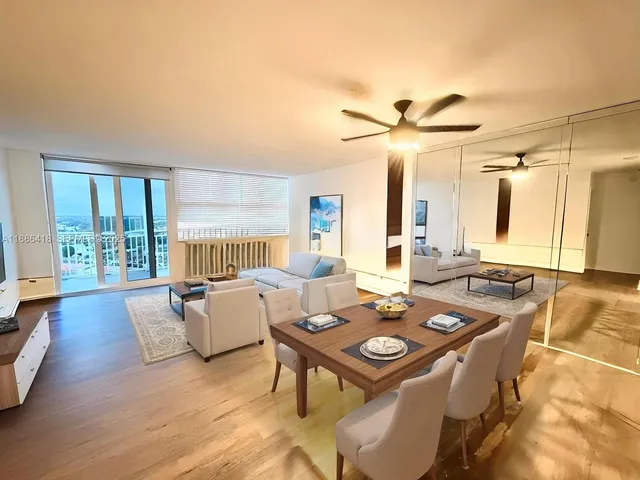 a living room with furniture a large window and wooden floor