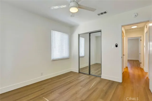 a view of empty room with wooden floor and fan