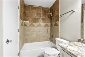 a bathroom with a granite countertop bathtub shower sink vanity and toilet