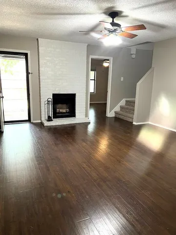 an empty room with wooden floor a fireplace and windows